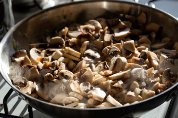 Frying chopped onion and mushrooms in pan