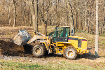 Obraz premium Excavator working with earth and sand in the forest near the construction site.