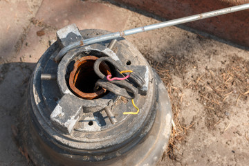 base of a broken street lamp with broken wires. Base of the light pole in the park, stand by, under repairing, broken.