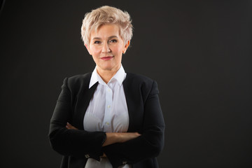 stylish elderly woman with a short haircut in a black suit on a black background