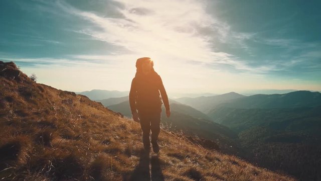 The male walking along the mountain on the bright sunset background. slow motion