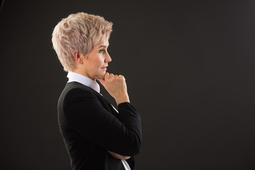 stylish elderly woman with a short haircut in a black suit on a black background