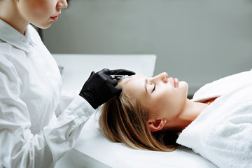 Beautiful woman getting lifting injection in forehead. Close-up woman face injection.