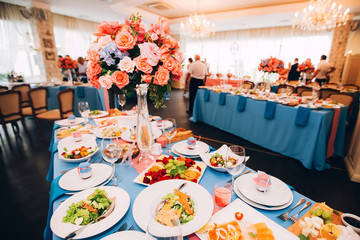 wedding decor in the style of boho. flower arrangements with roses, candles in glass candlesticks. table with pink tablecloth.
