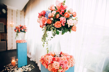 wedding decor in the style of boho. flower arrangements with roses, candles in glass candlesticks. table with pink tablecloth.