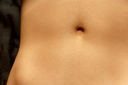 belly of a young man. Closeup - navel of the stomach - belly button. Slim nude young woman belly.