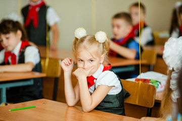 Two cute caucasian girls with two braids studying in sunny classroom with classmates. Knowledge lesson Concept. Day of knowledges. September, 1. Russia, Krasnodar