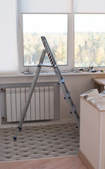 Stepladder stairs in apartment by window against the background of repair materials