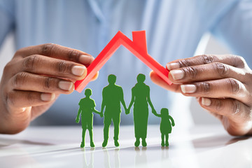 Person Protecting Family Figures With Roof
