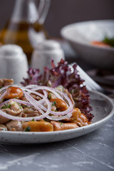 marinated mushrooms and onions in a plate on a grey background