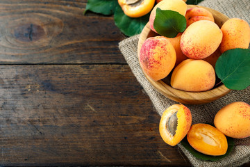 Delicious ripe apricots in a wooden bowl on the table close-up.