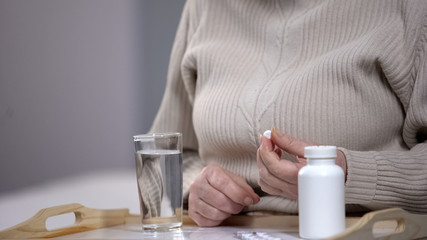 Aged woman taking pills, suffering from incurable disease, rehabilitation center
