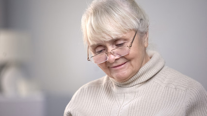 Elderly woman wearing eyeglasses and reading, vision problems, health care