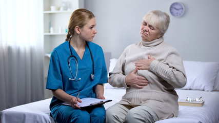 Elderly woman complaining to doctor on health problems, rehabilitation center