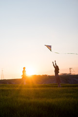 Fototapeta na wymiar man and woman playing with a kite at sunset