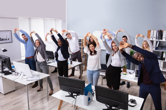 Young Businesspeople Doing Stretching Exercise At Workplace