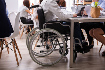 Fototapeta na wymiar Disabled Businessman Sitting On Wheelchair Using Laptop