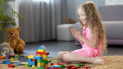 Naklejka premium Young girl playing organic wooden blocks, kids leisure at home, education