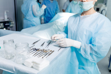 young doctor standing near the table full of different instrument. close up cropped photo.