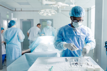 african male assistant preparing medical tools for performing operation. emergency help concept.