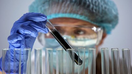 Researcher examining black substance, oil expertise and raw material quality
