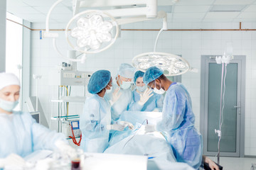 senior doctor with raised hands in gloves are ready to perform risky operation indoors.