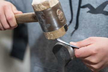 Handwerker mit Holzhammer bei Metallbearbeitung