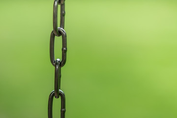 Close up of metal chain with blurred green nature lawn background.