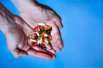 men's hands hold pills, vitamins, bada  isolated on blue background. Copy space