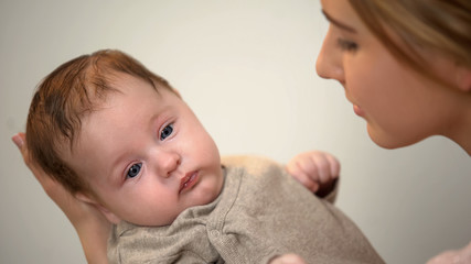 Beautiful lady holding little adorable child in arms, skin-to-skin contact
