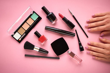 Different makeup products composition with hand on pink background