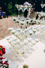 martini glass pyramid. glasses for liquor on the table. buffet table covered with a white tablecloth.