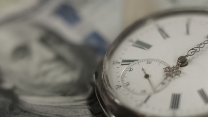 Ancient watch lying on american banknote, time is money, income and wealth