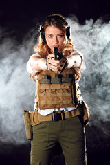 Calm and concentrated woman soldier possessing such features as stress resistance and good coordination of movements pointing at camera with gun in hands. Army, dedication, weapon, technology.