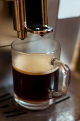 A cup of coffee in the coffee machine. The process of making coffee