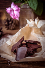 Still life with pieces of dark chocolate on wooden rustic background