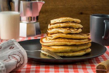 Delicious pancakes with milk and coffee for breakfast on the background of a beautiful tablecloth.