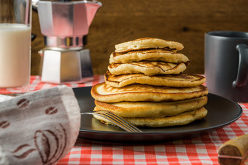 Delicious pancakes with milk and coffee for breakfast on the background of a beautiful tablecloth.