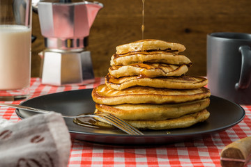 Delicious pancakes with milk and coffee for breakfast on the background of a beautiful tablecloth.