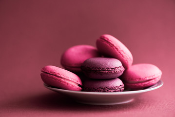 Obraz na płótnie Canvas Macarons. Colorful French Macaroons on dark pink background. Dessert or cookies still life.