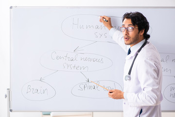 Young male doctor neurologist in front of whiteboard 