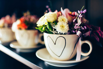 white cup with a heart on the shelf. bouquet of roses, carnations and asters.