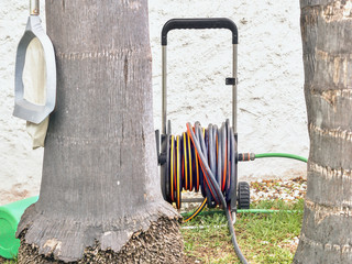 a garden hose wound up on a device to drive stands between two trees