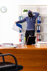 Male thief in balaclava in the office 