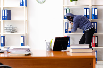 Male thief in balaclava in the office 