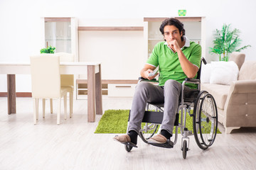 Young handsome man in wheelchair at home 