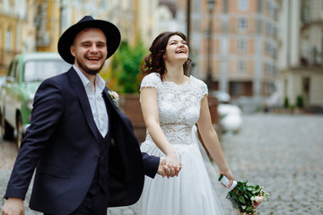 Caucasian happy smiling young couple walks at city and celebrate their marriage