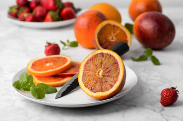 Blood orange slices on the plate with mint leaf and knife