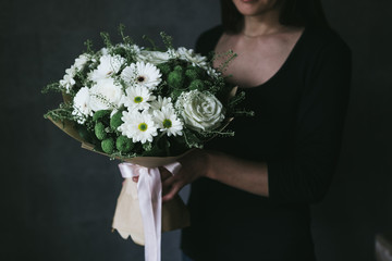 A bouquet of white chrysanthemums in the hands of a woman