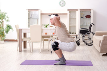 Injured young man doing exercises at home 